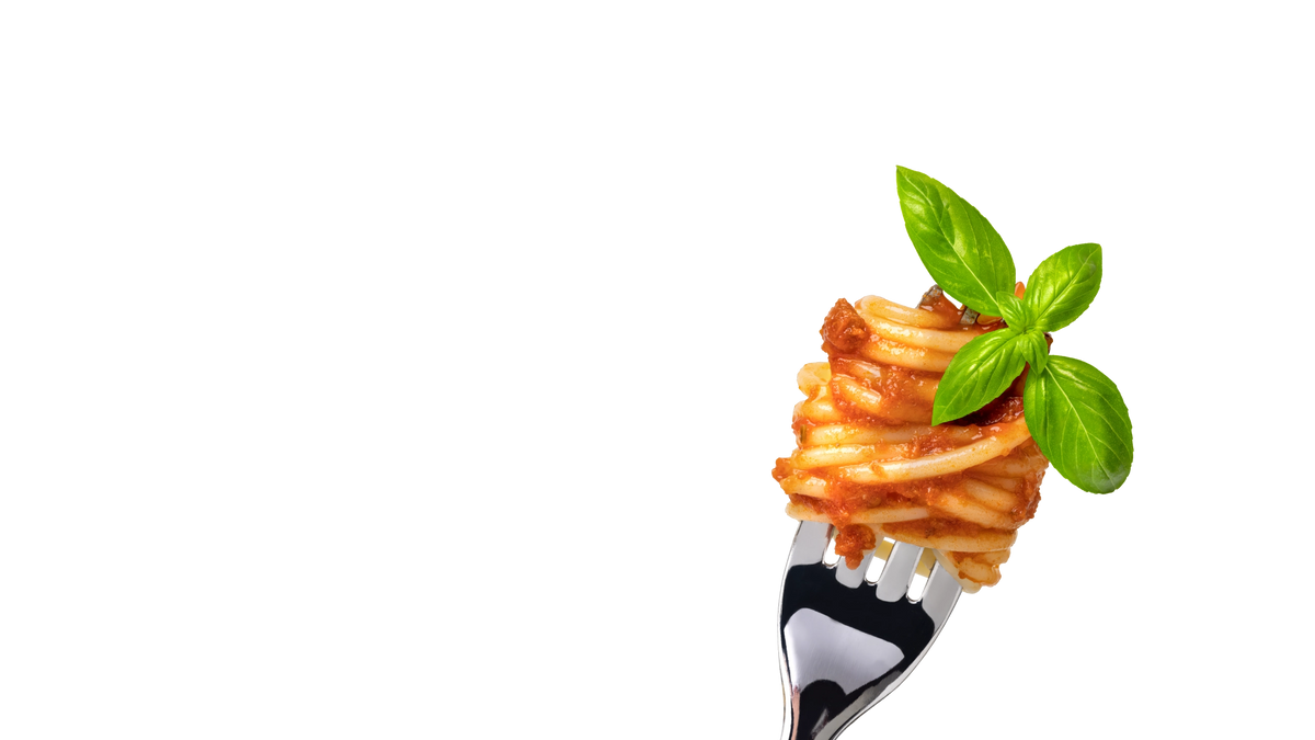 A close-up of spaghetti twirled on a fork, coated in red tomato sauce and topped with fresh green basil leaves, set against a solid white background.